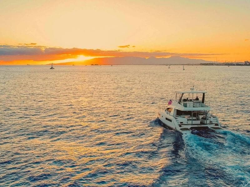 The Leopard power catamaran heading into a Hawaiian sunset, leaving a long wake.