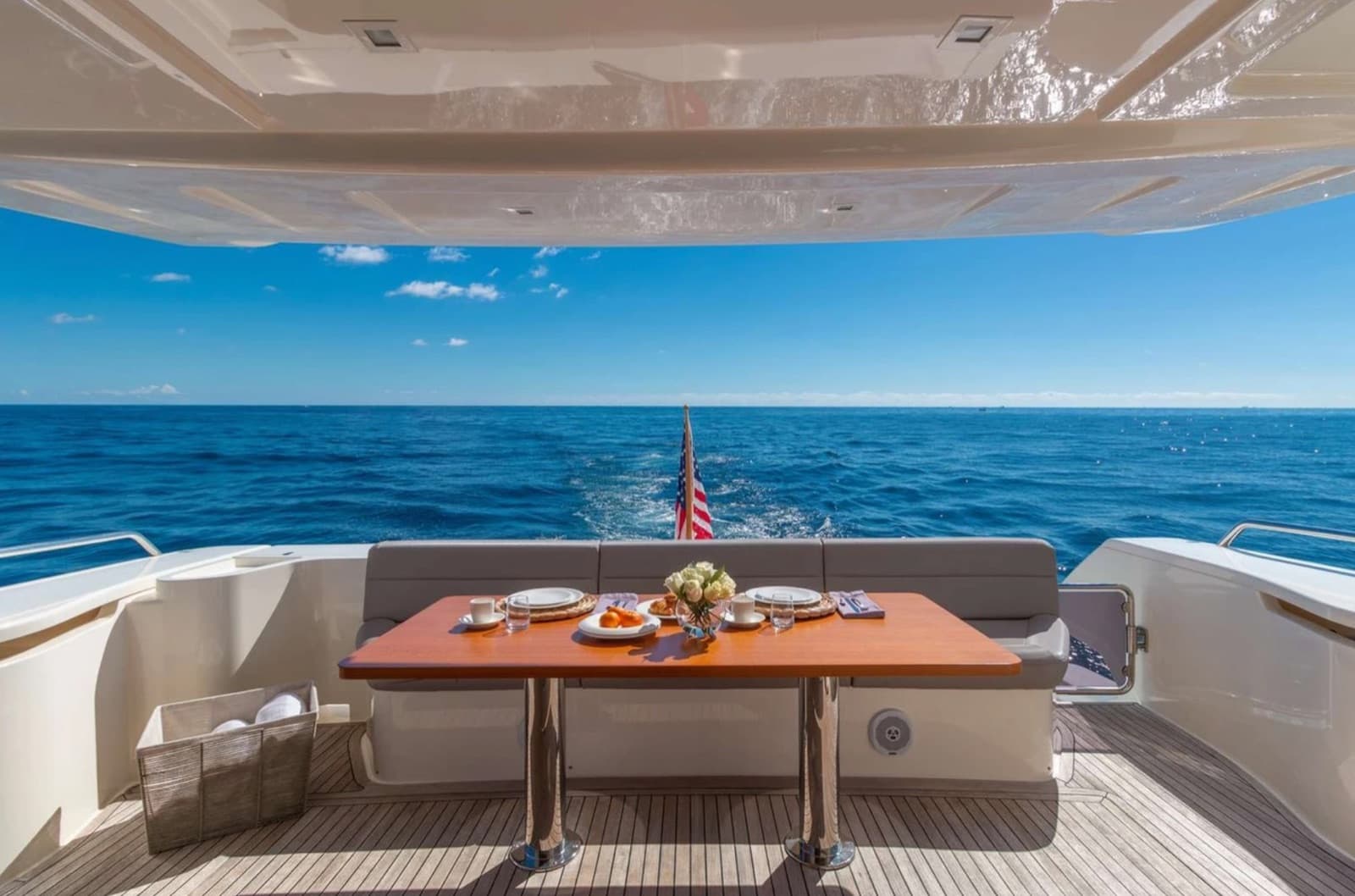 Aft-deck dining table set with the wake and the open ocean beyond.