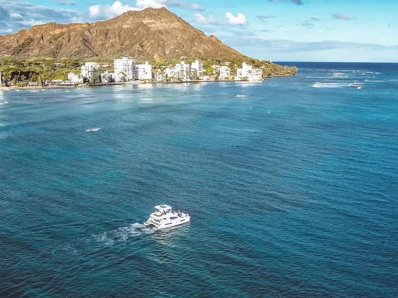 Aerial view of the Hilinaʻi, a 43-foot Leopard power catamaran, cruising past Waikiki and Diamond Head.