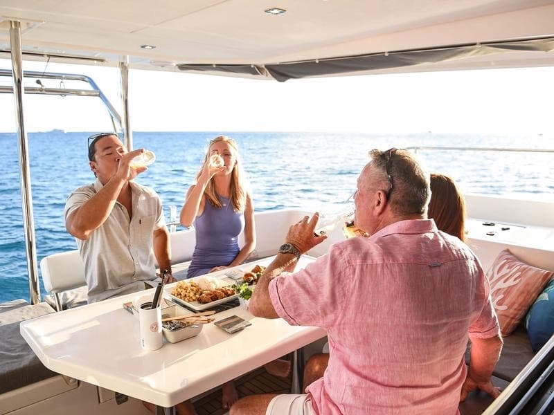 Guests sharing wine and lunch on the shaded aft deck.