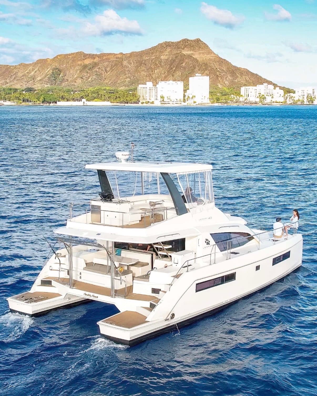 The Hilinaʻi at anchor off Diamond Head, twin hulls and flybridge in full view.