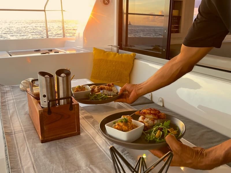 A plated island dinner served on deck at golden hour.