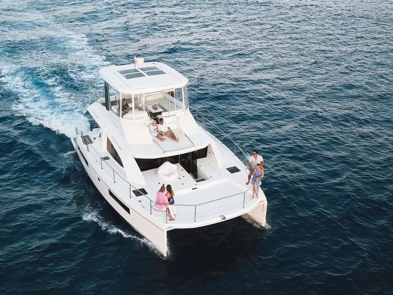 Guests relaxing on the foredeck as the power catamaran cruises the south shore.